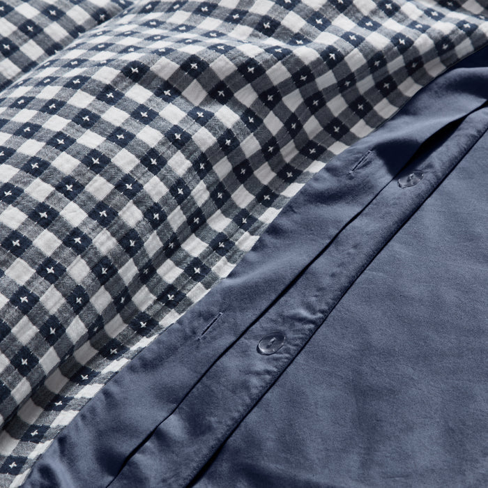 Close-up of blue checkered fabric with a buttoned blue garment underneath