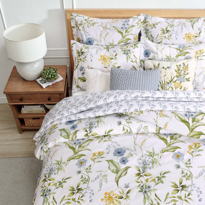 Floral bedding set on a bed with a nightstand and lamp in a bedroom setting.