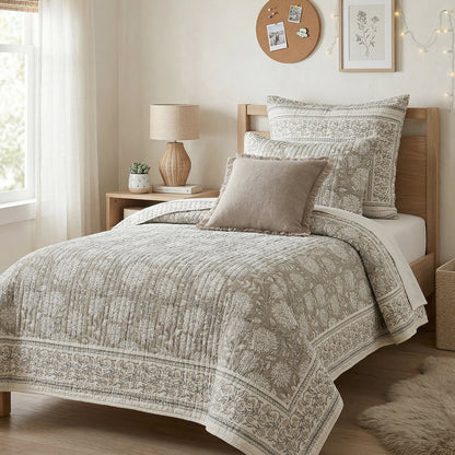 Neatly made bed with patterned bedding in a well-lit bedroom.