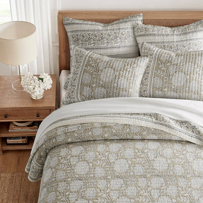Bed with patterned bedding and pillows in a bedroom setting.