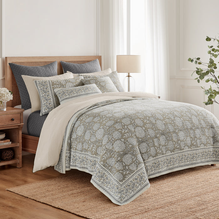 Bedroom with floral-patterned comforter and pillows on a bed.
