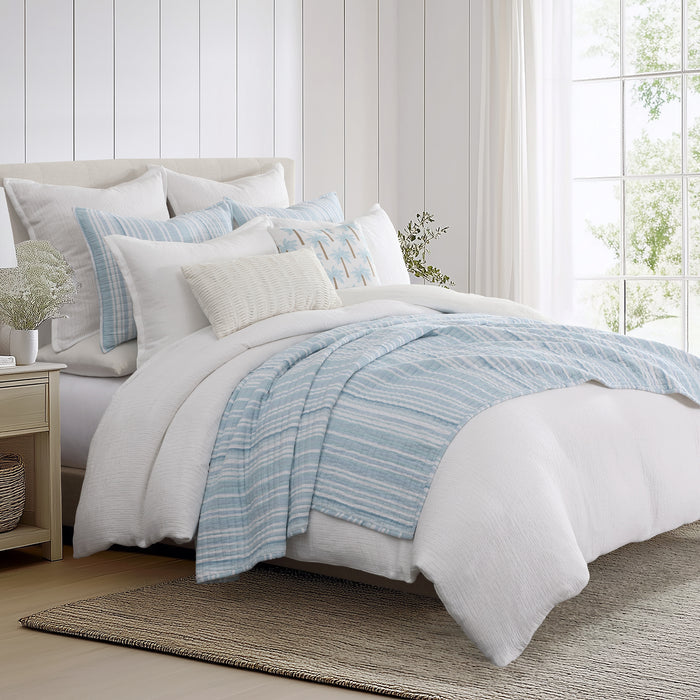 Boracay Stripe Muslin Quilt Set displayed on a bed with blue stripes and white bedding for a coastal bedroom aesthetic.