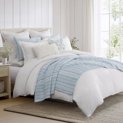 Boracay Stripe Muslin Quilt Set displayed on a bed with blue stripes and white bedding for a coastal bedroom aesthetic.