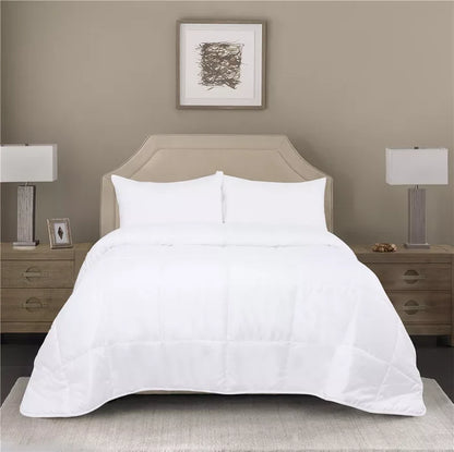 White quilted comforter on beige upholstered bed frame with matching nightstands and lamps