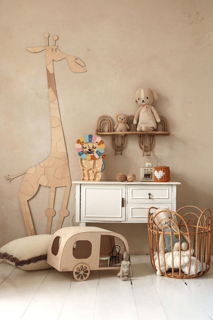 Natural wood giraffe wall decoration beside white dresser with shelves holding toys and nursery accessories