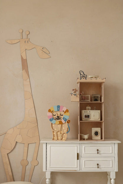 Wooden giraffe wall decor next to wooden shelving unit with toy kitchen setup and decorative items