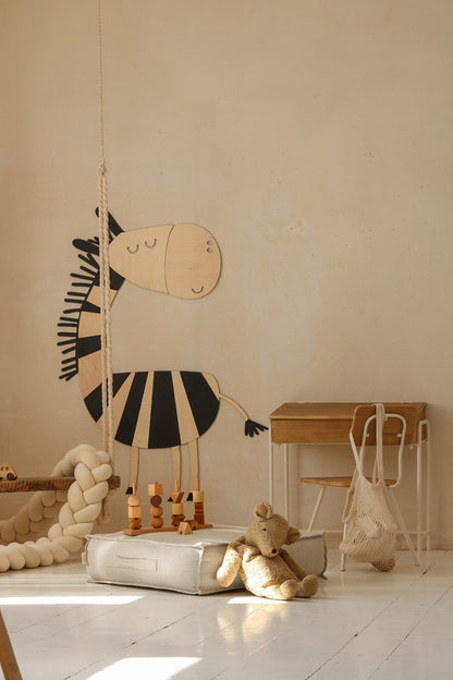 Wooden zebra wall decoration shown at an angle with children's furniture below
