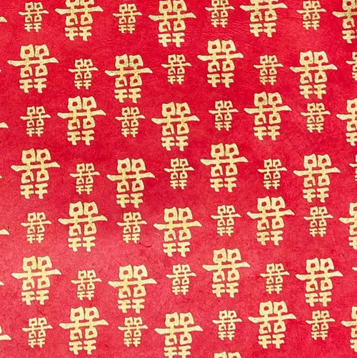 Red paper with a repeating pattern of gold Chinese double happiness symbols.