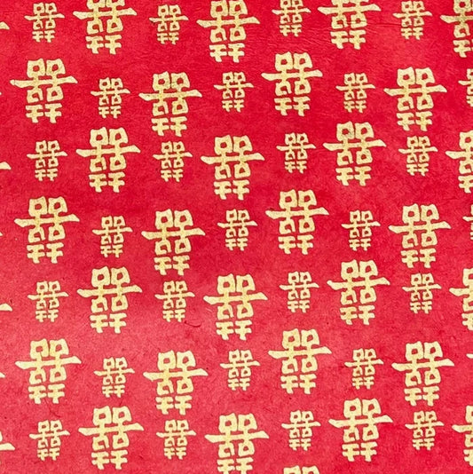 Red paper with a repeating pattern of gold Chinese double happiness symbols.