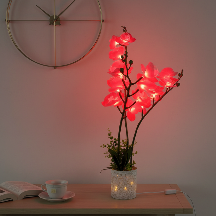Glowing pink orchid LED lamp in crackle vase on wooden table, ambient home decor lighting