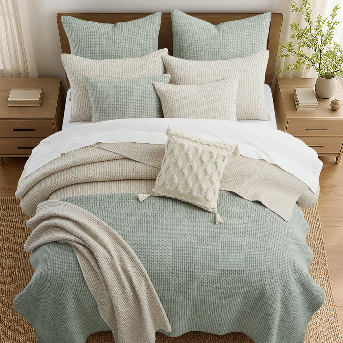 Neatly made bed with light-colored bedding and pillows in a bedroom setting.