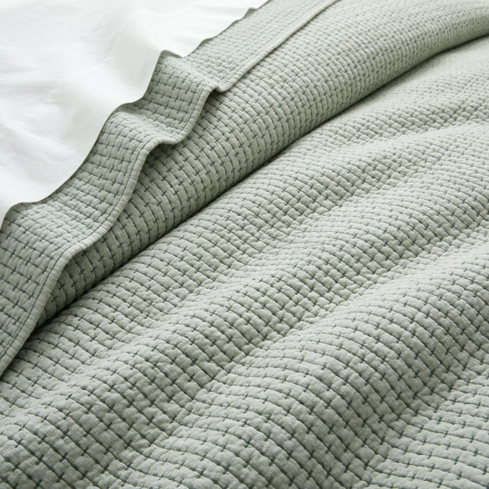 Close-up of a textured light green blanket on a white background