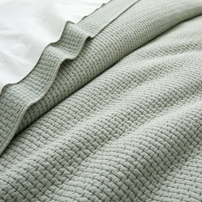 Close-up of a textured light green blanket on a white background