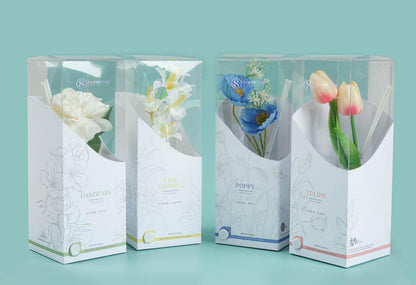 Four boxed reed diffusers with artificial flowers: gardenia, lily jasmine, poppy, and tulips.