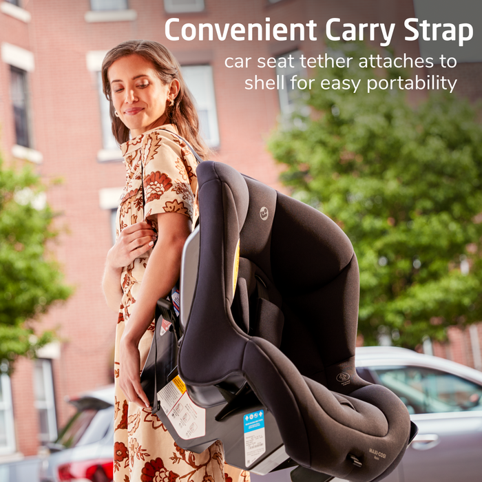 Woman holding a car seat with a convenient carry strap feature, outdoors.