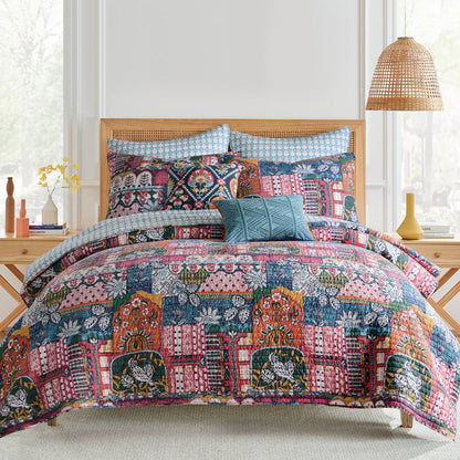 Roshita Quilt Set featuring vibrant boho patchwork design on bed with decorative pillows and natural ambiance.