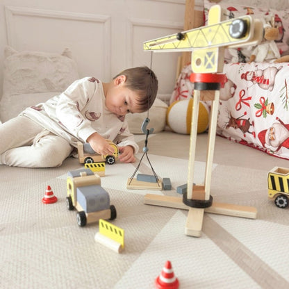 Child operating wooden crane to lift construction materials during imaginative play session