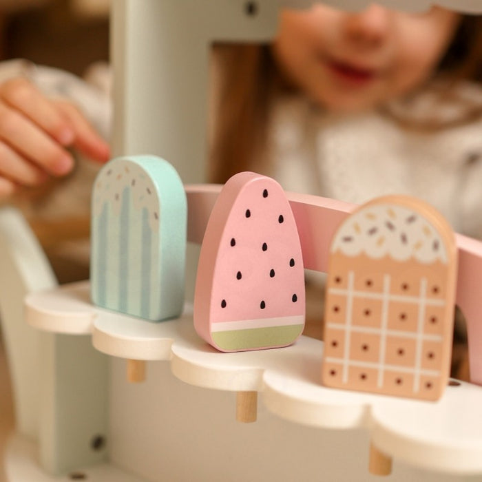 Close-up of pastel wooden ice cream scoops in mint, pink, and natural wood tones